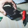 Een telefoon wordt gerepareerd, waarbij het scherm is losgemaakt, met een schroevendraaier en onderdelen op de tafel voor telefoon scherm reparatie prijs