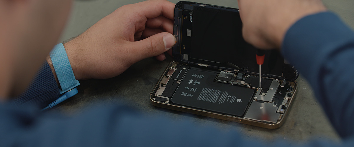 Technicus voert een iPhone scherm reparatie uit met een precisieschroevendraaier.